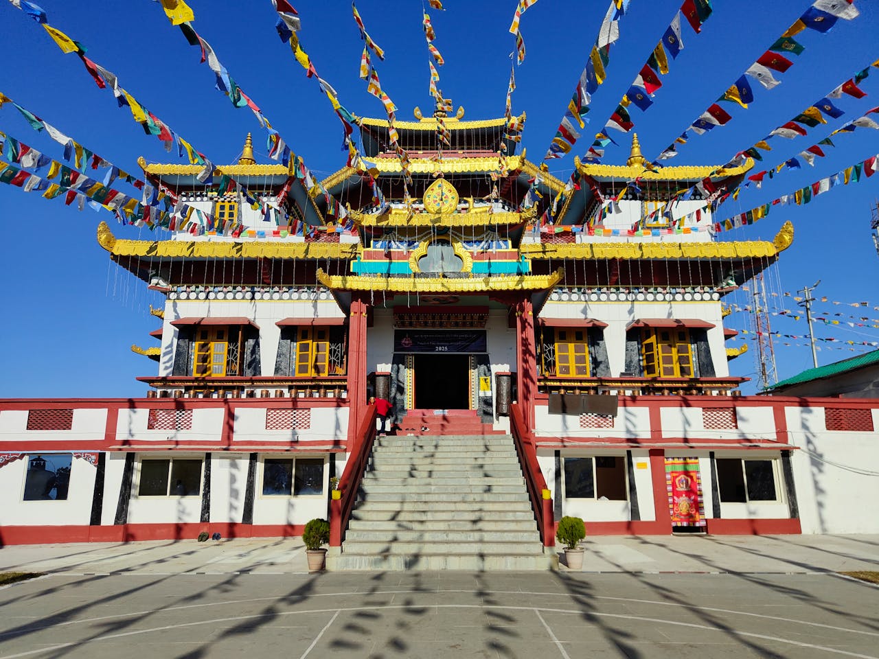 Ghoom Monastery in Darjeeling with colorful prayer flags and clear blue sky.